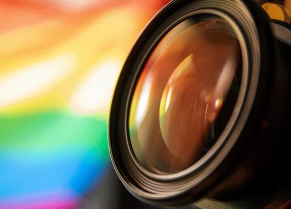 Gros plan sur une lentille d’objectif photo avec un arrière-plan coloré, symbolisant la passion pour la photographie.