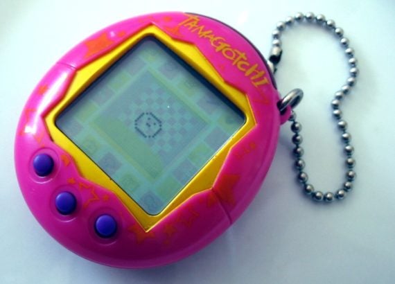 Tamagotchi rose avec écran et chaîne métallique.