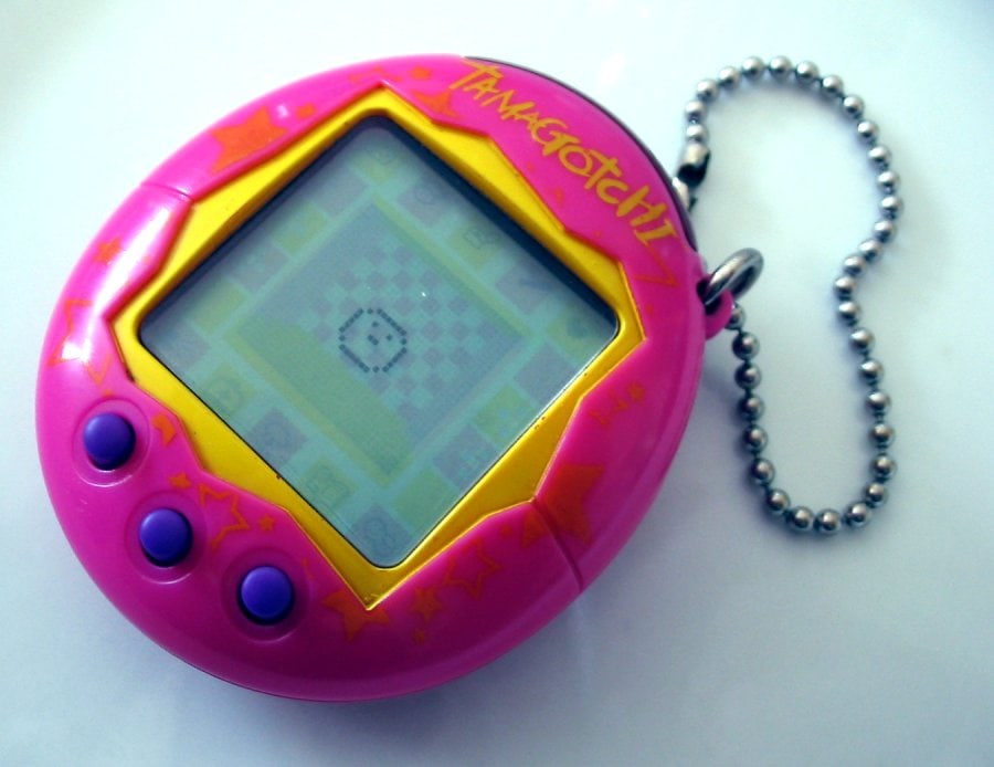 Tamagotchi rose avec écran et chaîne métallique.