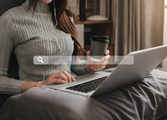 Femme utilisant un ordinateur portable avec une tasse de café et une barre de recherche affichée, illustrant les recherches Google de 2022.