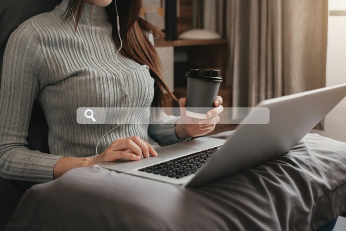 Femme utilisant un ordinateur portable avec une tasse de café et une barre de recherche affichée, illustrant les recherches Google de 2022.