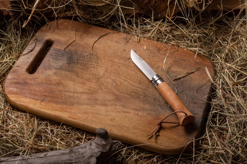 Couteau pliant en bois posé sur une planche en bois, outil essentiel pour la survie sur une île déserte.