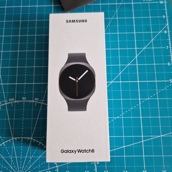 Boîte de la Samsung Galaxy Watch 8 sur un tapis de découpe bleu