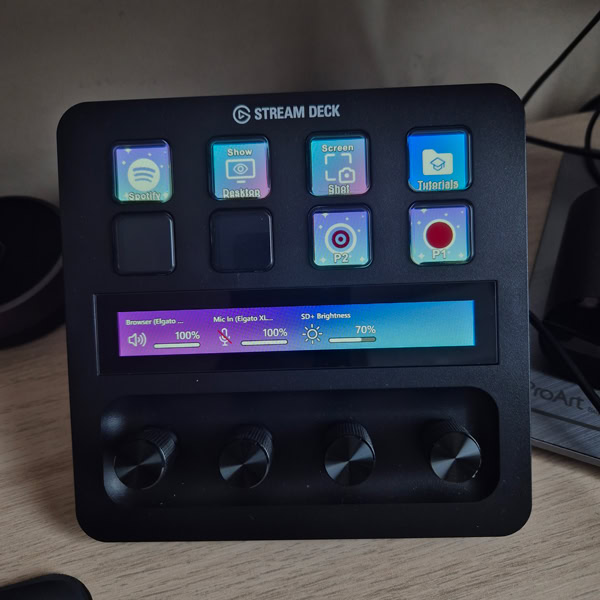 Stream Deck+ allumé sur le bureau avec boutons personnalisés (Spotify, Show Desktop, Screenshot) et barre tactile affichant les niveaux audio et de luminosité