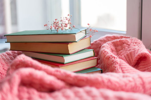 Pile de livres papier posée sur un plaid rose